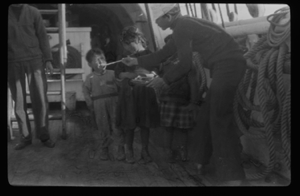 Image of Crewmen on deck with three children